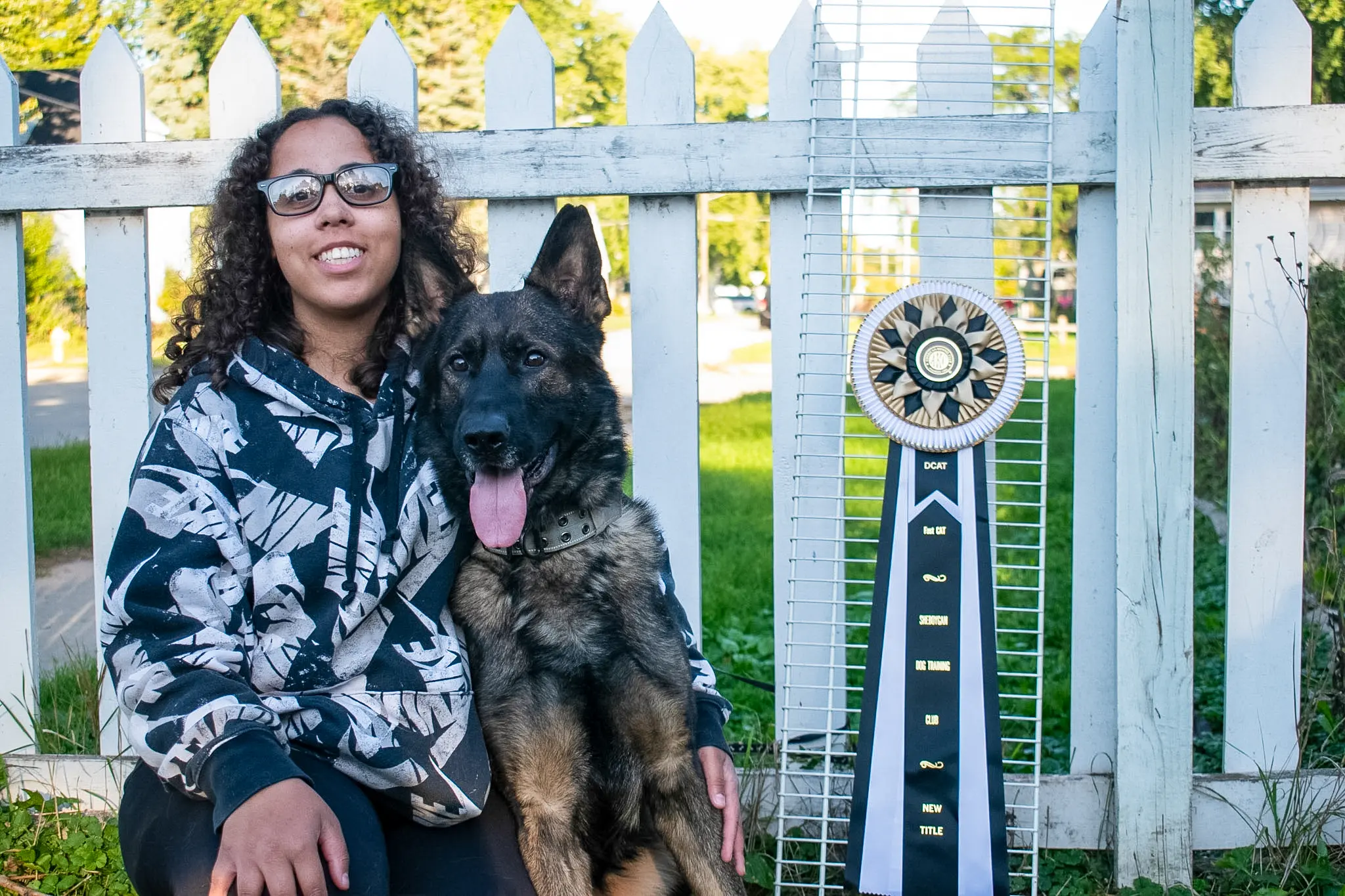 German Shepherd stud dog: German Shepherd sitting beside a person with a trophy nearby